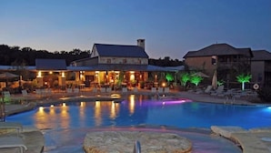 Une piscine dotée d’un espace de jacuzzi circulaire, de chaises longues et d’un bâtiment avec des espaces de détente en plein air.