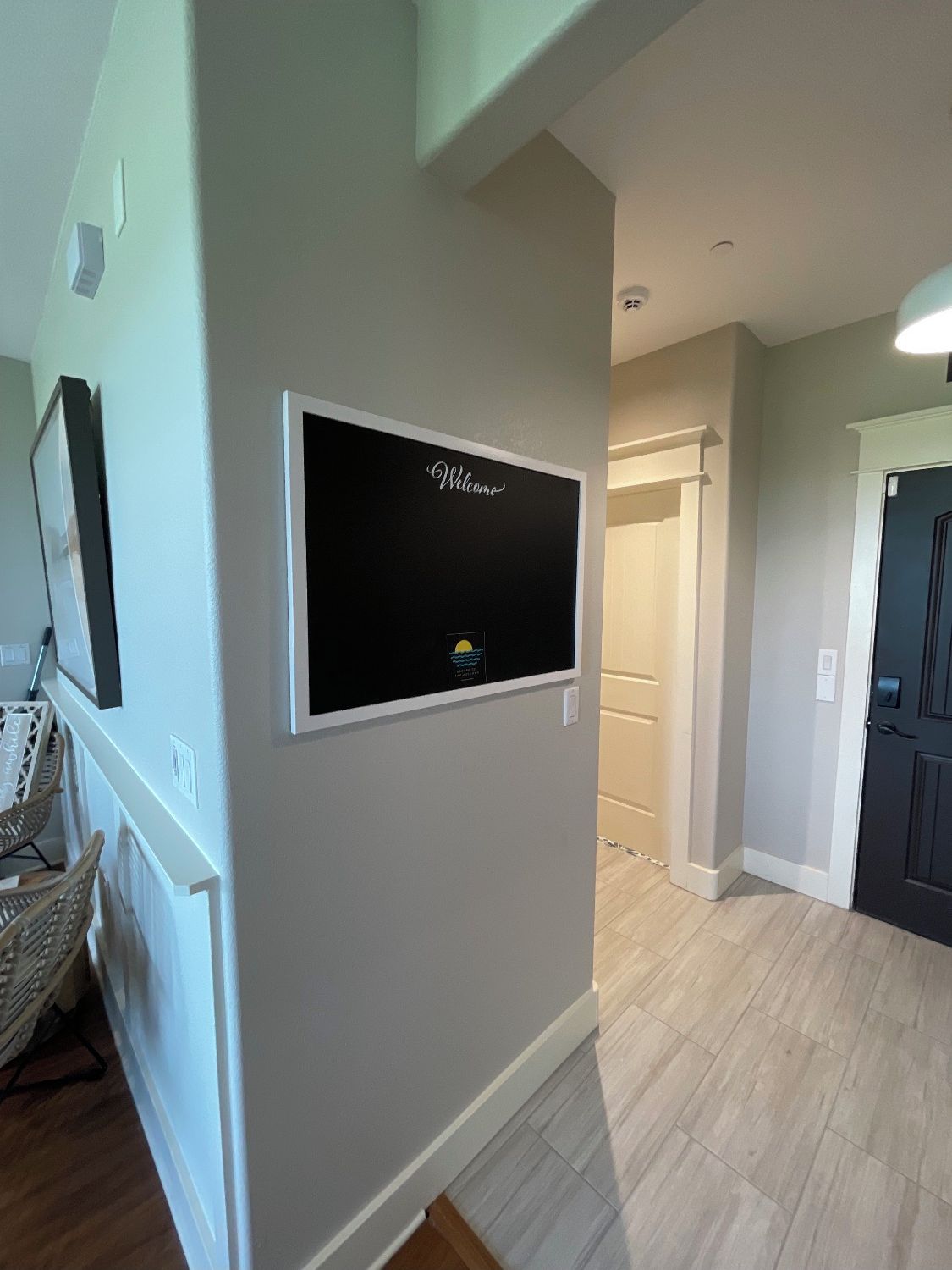 A hallway with a welcome sign, a door, and a chair.