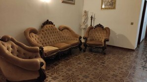 Una habitació amb tres butaques ornamentades i un sofà amb respatller amb borles.
