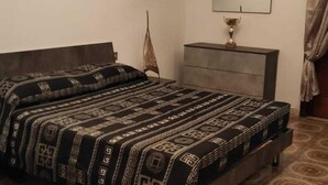 Un dormitori amb llit, envà, mirall i una catifes amb dibuixos.