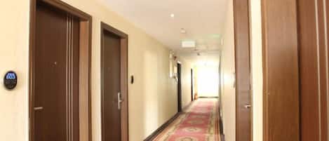 A hotel corridor with wooden doors, a patterned carpet, and a sign indicating room number 600.