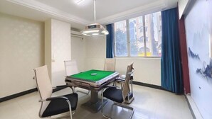 A room with a pool table, chairs, a ceiling light fixture, and a window with curtains.