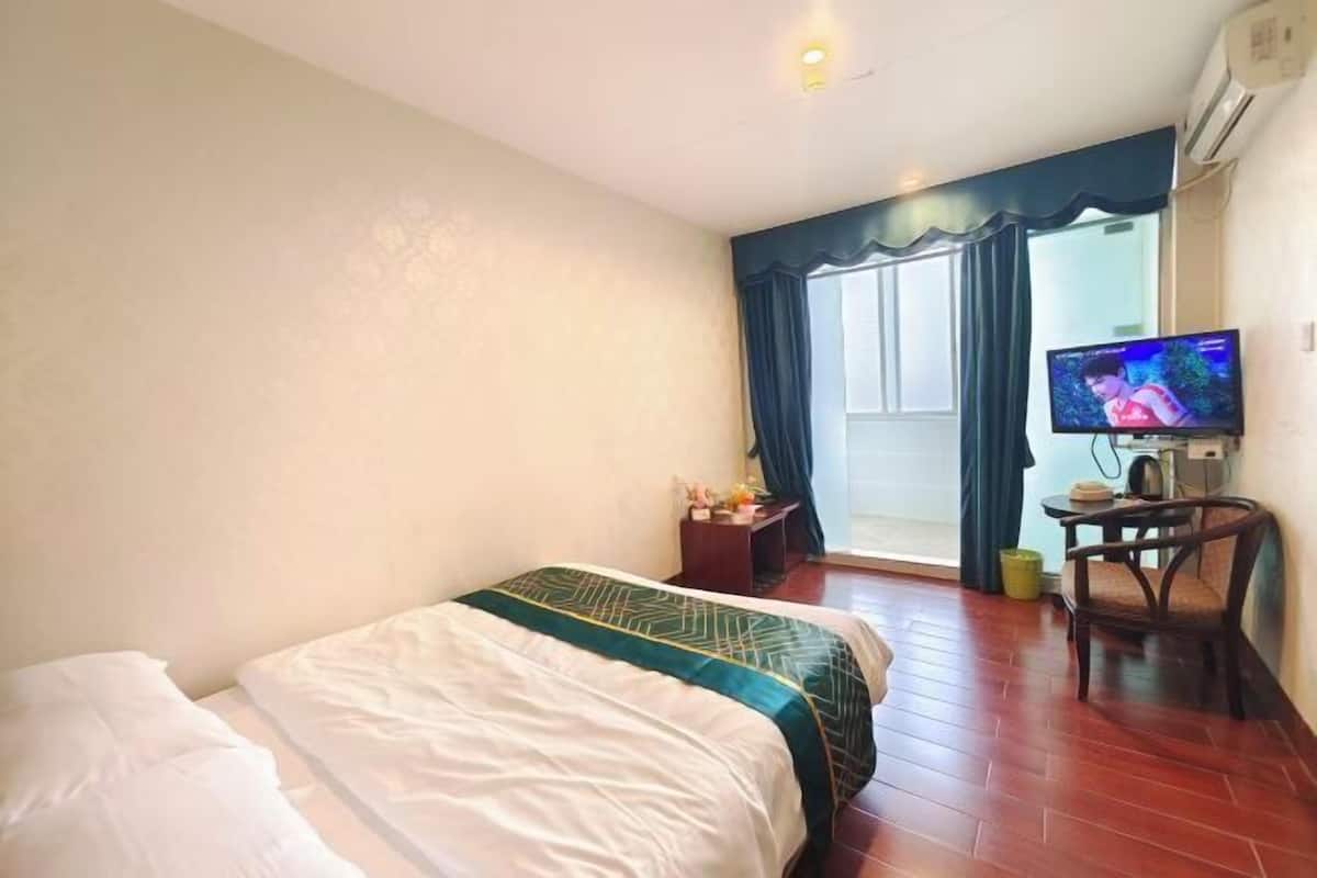 A hotel room with a bed, a television, a chair, and a window with curtains.