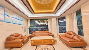A spacious lobby with leather sofas, a central coffee table, and a chandelier.