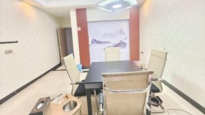A conference room with a long table, chairs, a projector, and a wall-mounted screen.