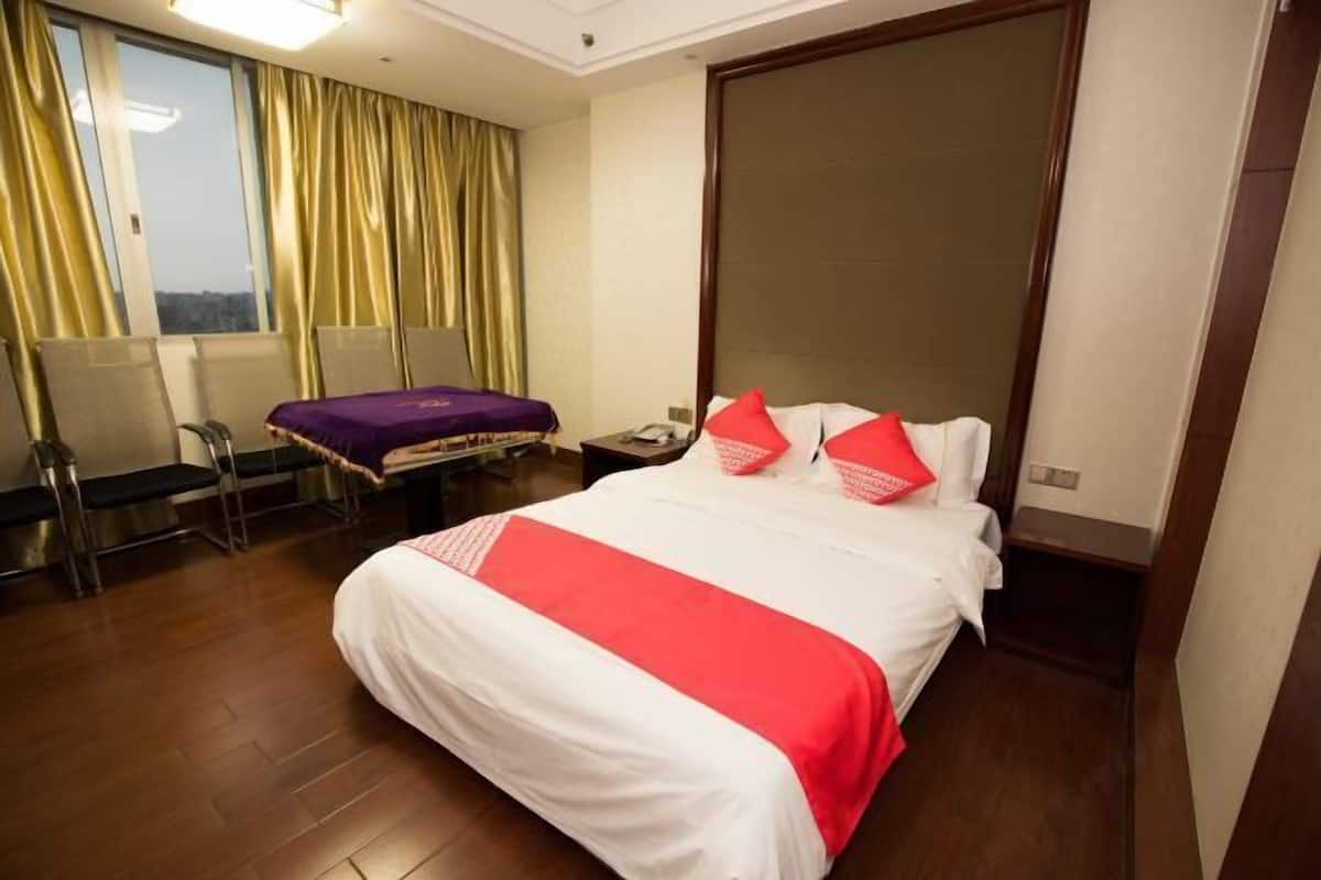 A hotel room with a large bed, a desk, and a chair.
