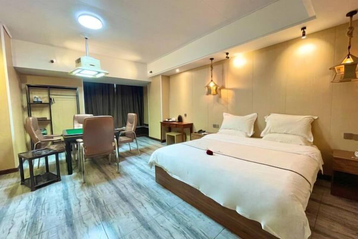 A hotel room with a large bed, a desk, two chairs, and a small table.
