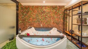 Un cuarto de spa con pared de piedra, una bañera y repisas con artículos de aseo.