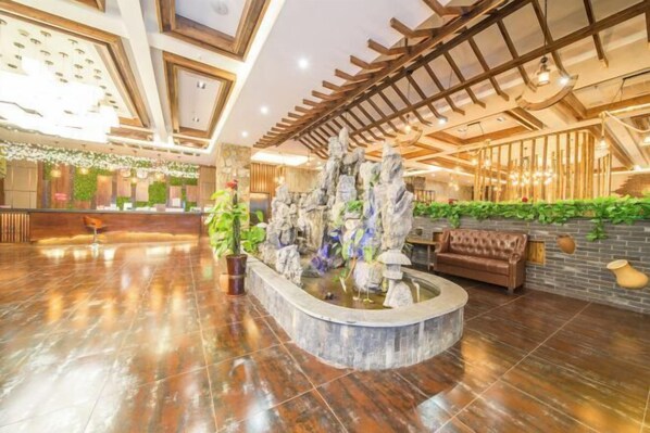 A spacious lobby with a central water feature, wooden ceiling beams, and a reception desk. - Sofia Hotel (Wenchang)