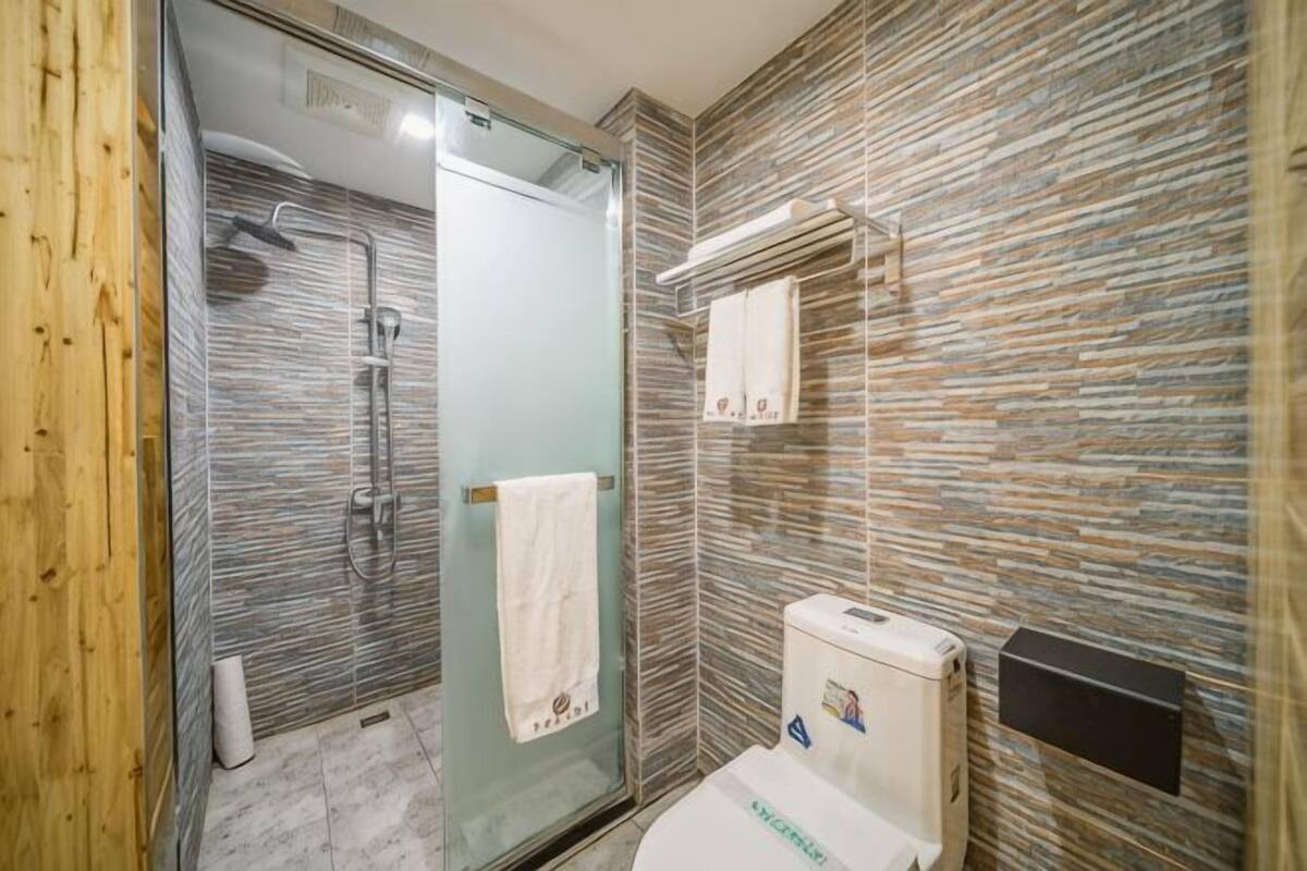 Uma casa de banho moderna com cabine de duche em vidro, sanita e um porta-toalhas.