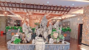 Un vestíbulo con una formación rocosa central, un mostrador de recepción y una pared de piedra.
