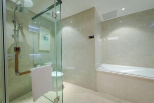 Un baño moderno con ducha envuelta en vidrio, una bañera blanca y un inodoro.
