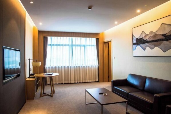 Ein modernes Hotelzimmer mit einem großen Fenster, einer Couch, einem Couchtisch und einem Gemälde an der Wand.