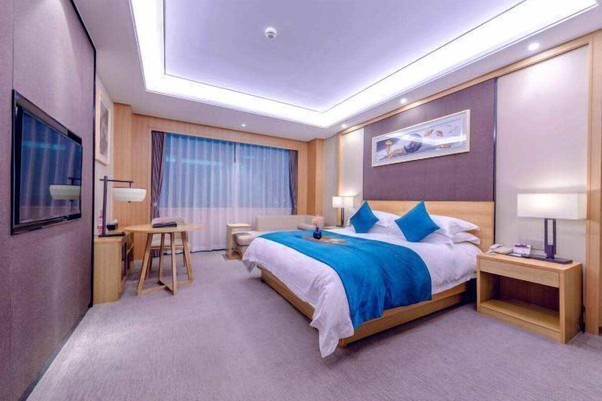 A modern hotel room with a large bed, bedside tables, a desk, and a chair.