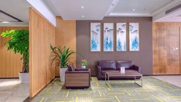 A modern lobby with a reception desk, seating area, and decorative wall art.