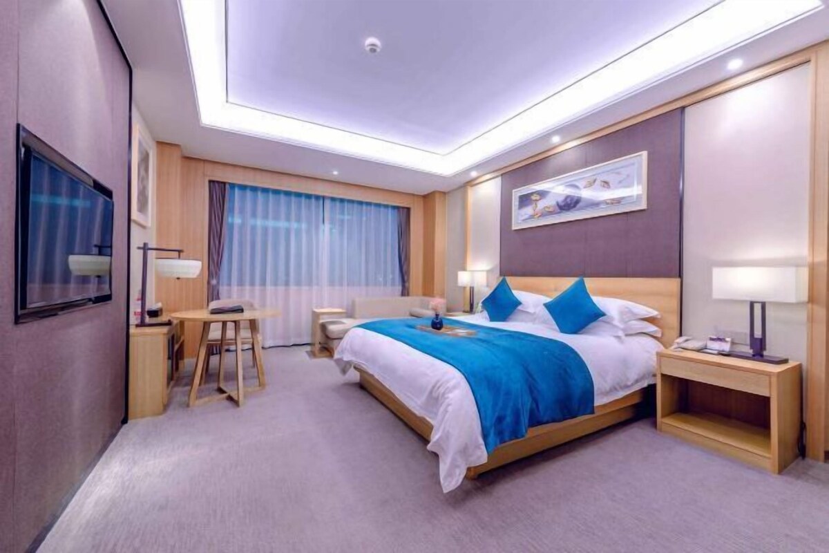 Ein Hotelzimmer mit Bett, Nachttischen, Schreibtisch und Stuhl.