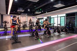 A gym with stationary bikes and mirrors, a large window, and a modern ceiling design. - TaiYun Easeful Hotel (Linhai)
