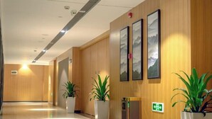 En modern hotellobby med träpanel på väggarna, krukväxter och inramade konstverk.