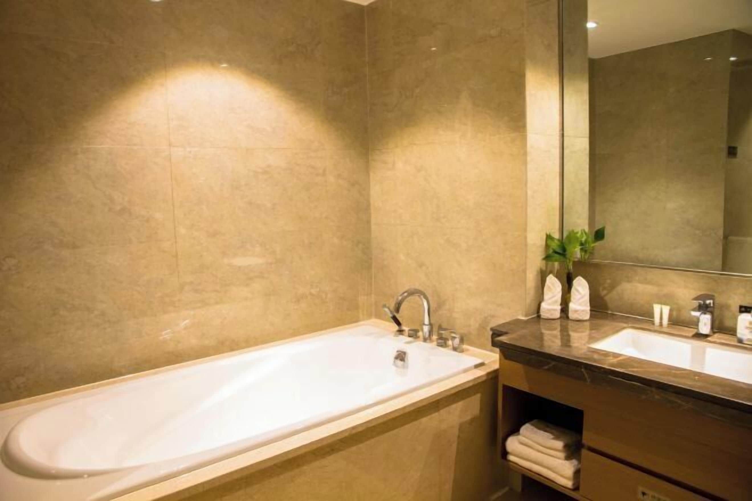 A modern bathroom with a large bathtub, a double sink, and a mirror.