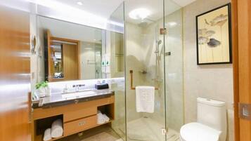 A modern bathroom with a glass-enclosed shower, a white toilet, and a vanity with a mirror.