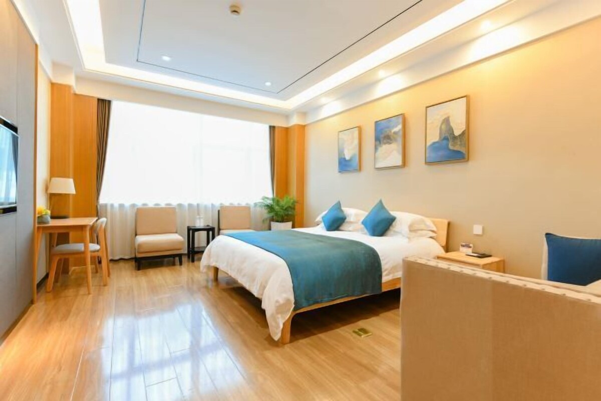 Ein Hotelzimmer mit Bett, Schreibtisch, Stuhl, Fernseher und Wandbild.