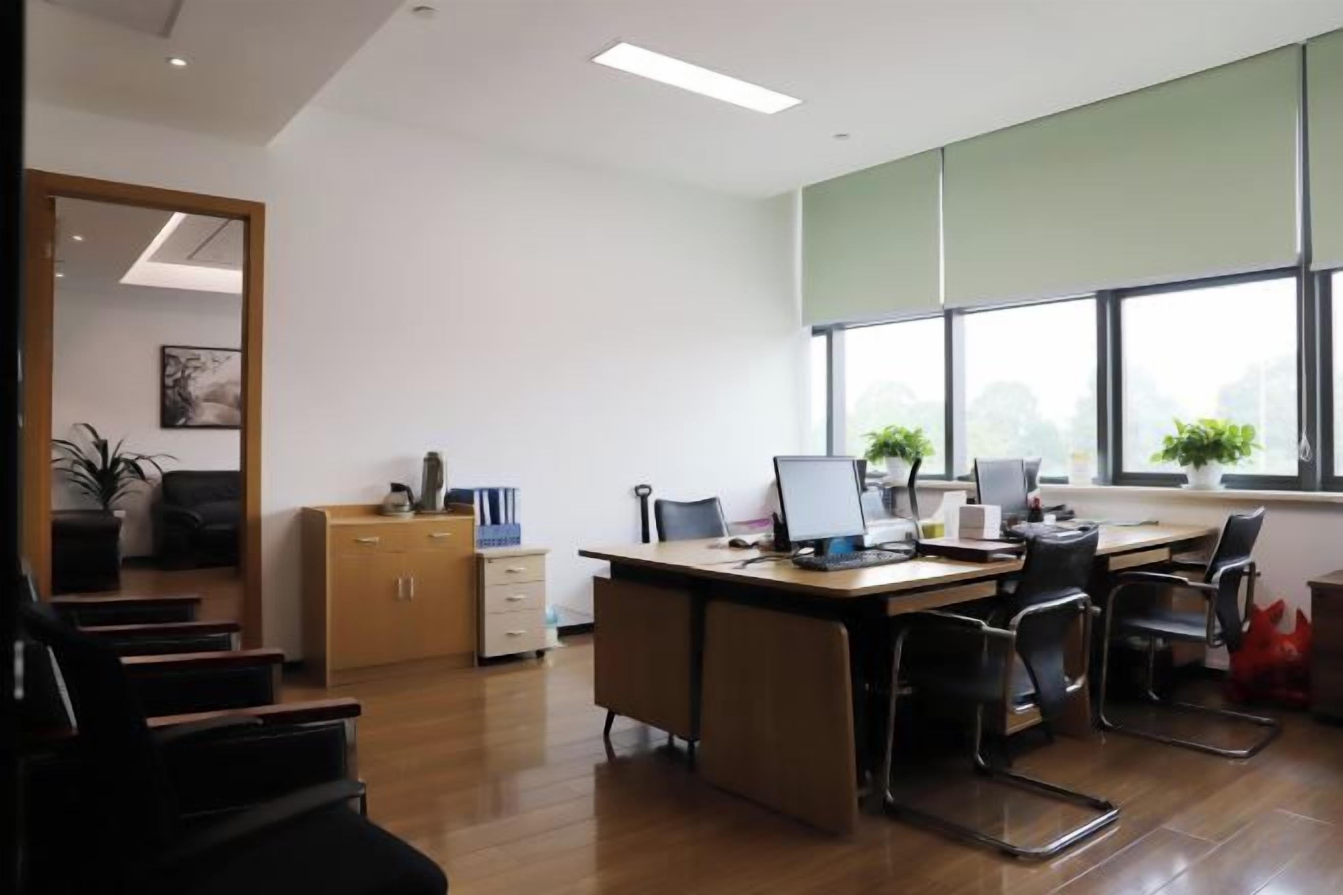 A modern office with a desk, chairs, and a large window.