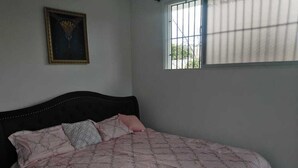 A bedroom with a bed, a window with bars, and a framed picture on the wall. - close to the sea, Colonial Zone, restaurants and Museums (Santo Domingo)