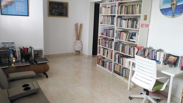 A room with a bookshelf, a desk, and a chair. There is a sign on the wall and a painting. - close to the sea, Colonial Zone, restaurants and Museums (Santo Domingo)