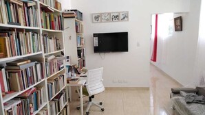 A room with a bookshelf, a desk with a chair, a bed, and a TV mounted on the wall. - close to the sea, Colonial Zone, restaurants and Museums (Santo Domingo)