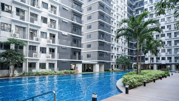 A modern apartment building with a swimming pool, balconies, and greenery.