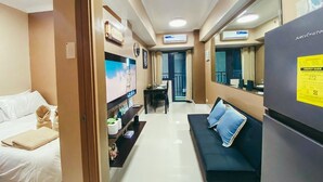 A hotel room with a bed, a sofa, a dining area, and a kitchen area.