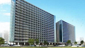 A modern high-rise building with a grid-like facade, multiple balconies, and a clear sky.