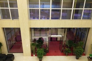 A lobby with a red carpet, potted plants, and a glass door entrance. - Huangsheng Hotel (Wuchuan)