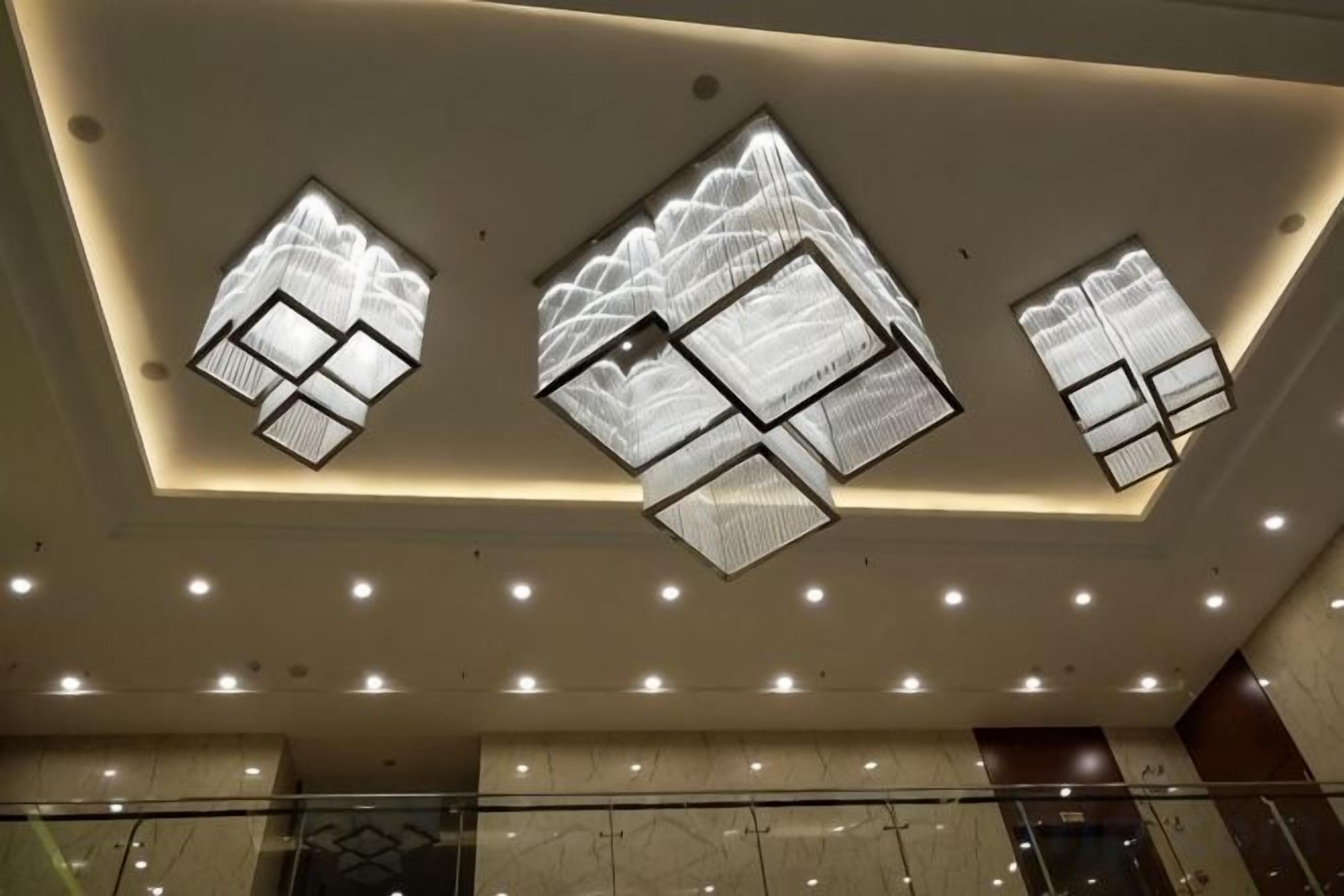 A ceiling with recessed lighting and three geometric skylight designs.