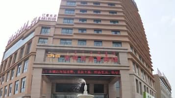 A multi-story hotel with a prominent entrance, a fountain, and several signs indicating amenities and services.