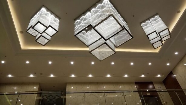 A modern interior with recessed lighting, geometric ceiling designs, and a marble floor. - Huangsheng Hotel (Wuchuan)