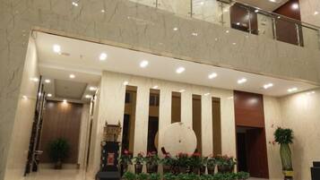 A hotel lobby with a marble floor, a reception desk, and a large decorative wall.