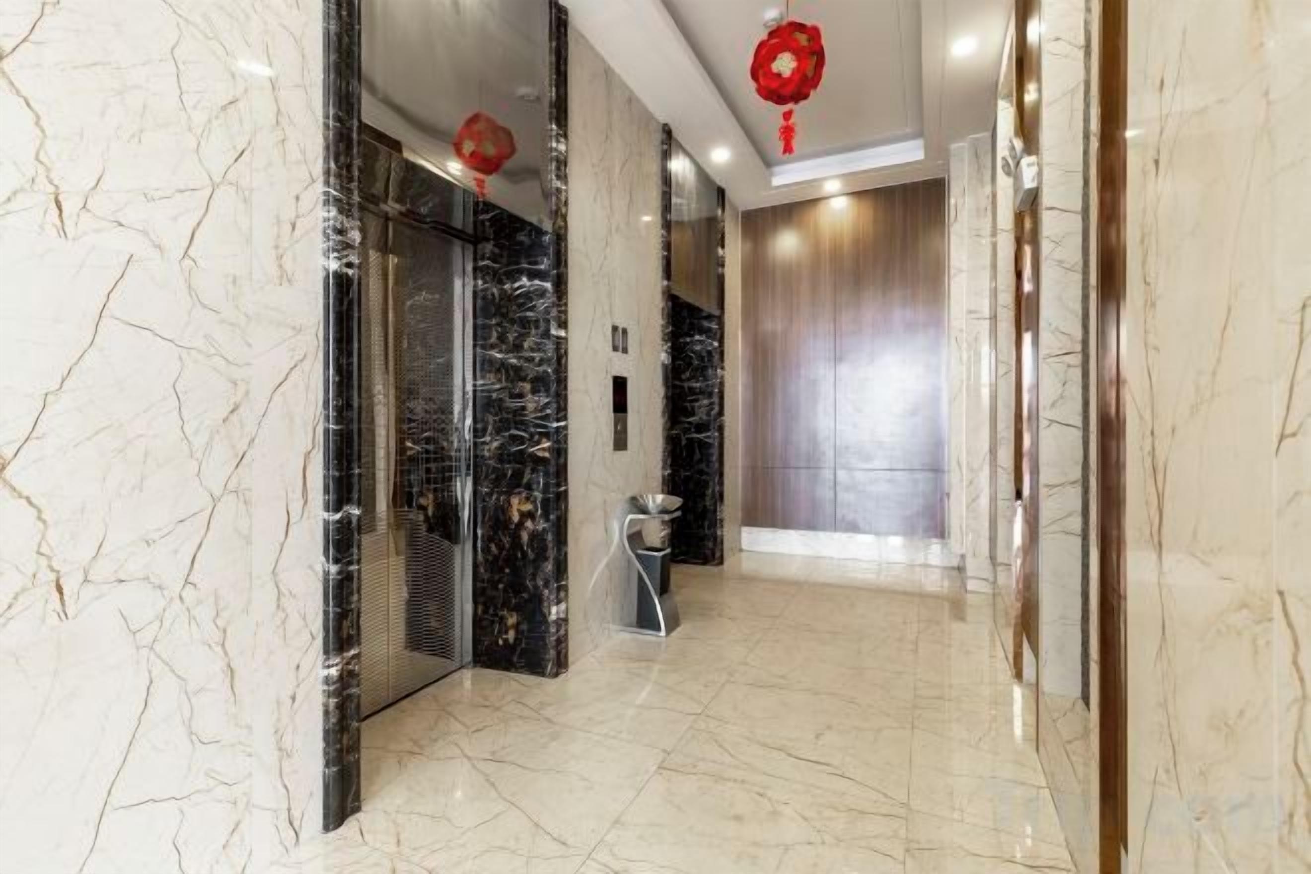 A hallway with marble flooring, a trash bin, and a red hanging ornament.