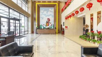 A hotel lobby with a reception desk, seating area, and potted plants.