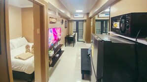 Habitación de hotel con cama, televisión, microondas y un pequeño comedor.