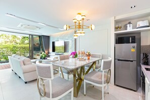 A modern kitchen with a dining area, a built-in refrigerator, and a large window overlooking greenery. - 3br Luxury Beachfront Pool Villa (Rawai)