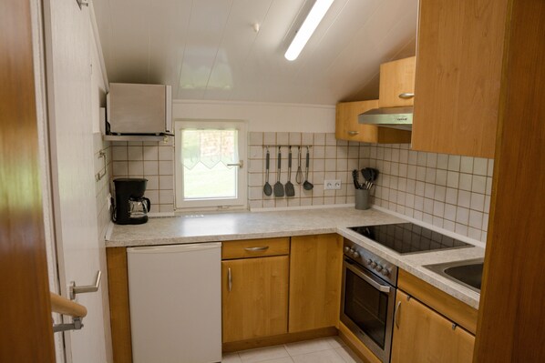 A kitchen with wooden cabinets, a refrigerator, a stove, and a sink.