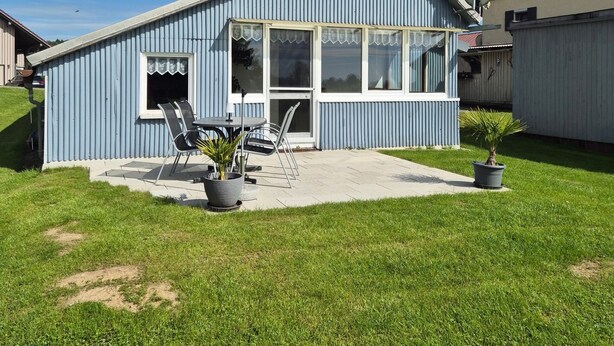 A single-story building with a sloped roof, a large window, and a patio area with outdoor furniture. - Apartment 'Kleiner Spatz' with Terrace, Shared Garden & Wi-Fi (Leutkirch im Allgäu)