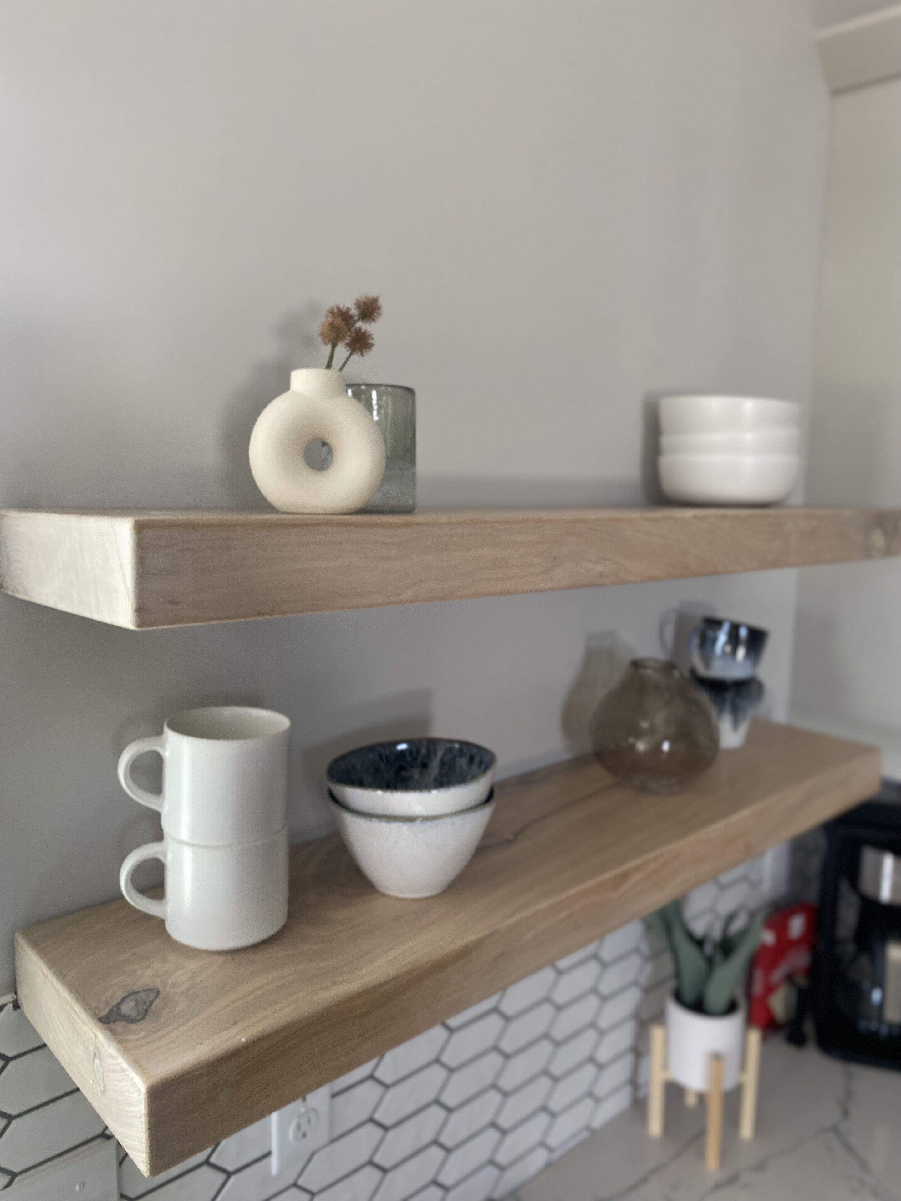 A kitchen with wooden shelves holding various kitchenware.