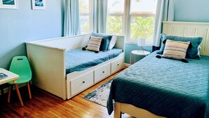 A room with two beds, a chair, a table, and a window with curtains. - Midtown Ventura Family & Pet Friendly Cottage (Ventura)