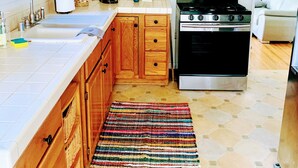 A kitchen with wooden cabinets, a microwave, a stove, and a tiled backsplash. - Midtown Ventura Family & Pet Friendly Cottage (Ventura)