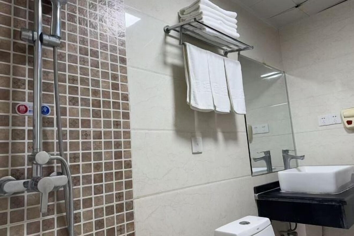 Un baño con ducha, lavamanos, toallero y espejo.