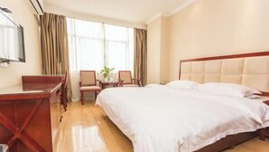 Een hotelkamer met een bed, bureau, stoelen en een raam met gordijnen.