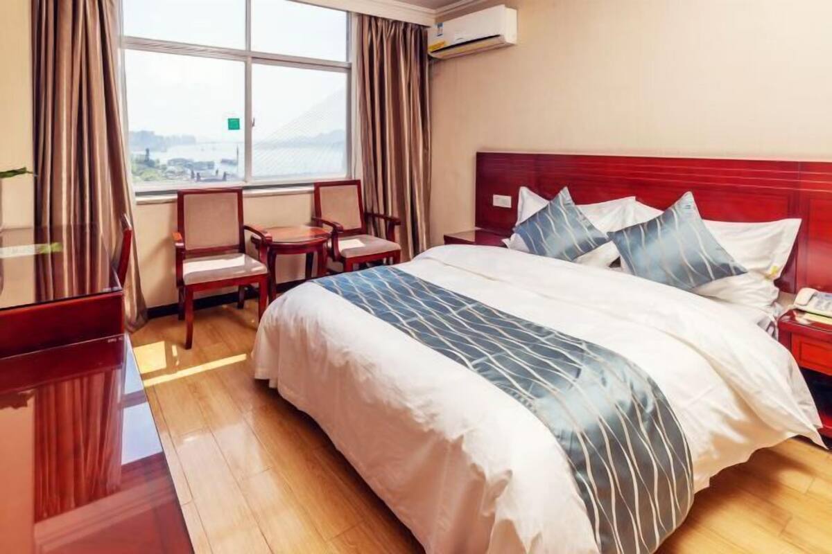 Een hotelkamer met een bed, een bureau, een stoel en een raam met uitzicht.