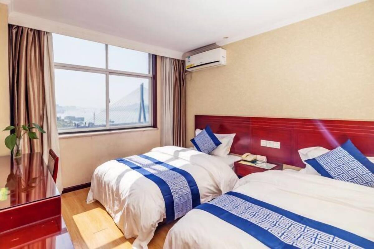 Hotelkamer met twee bedden, een bureau, een airconditioner en een raam met uitzicht.